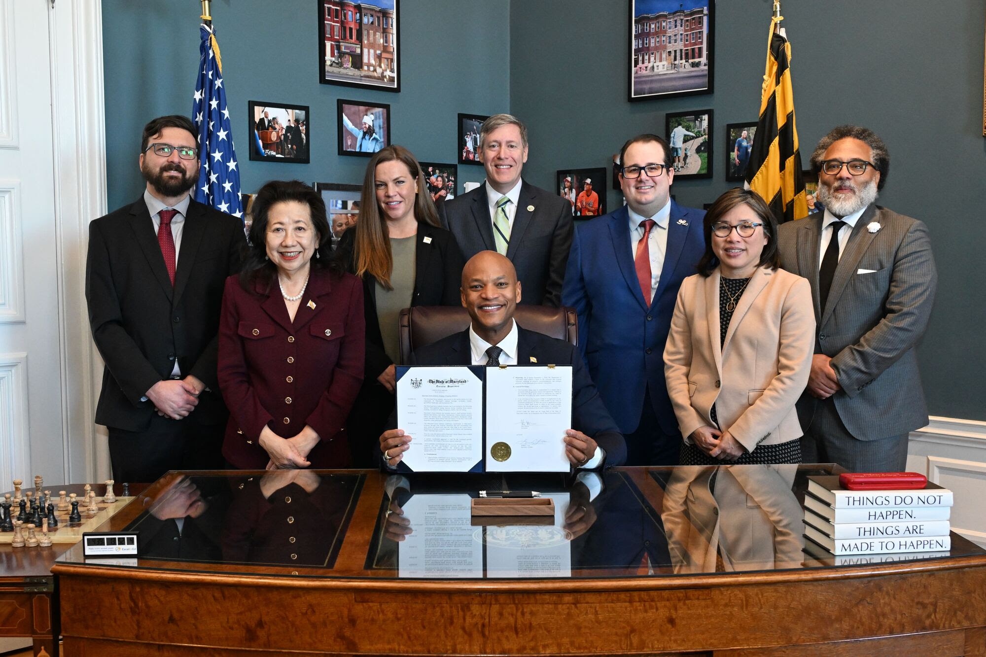 Seven officials in business attire join Maryland Governor Wes Moore for a group portrait also displaying a signed executive order.