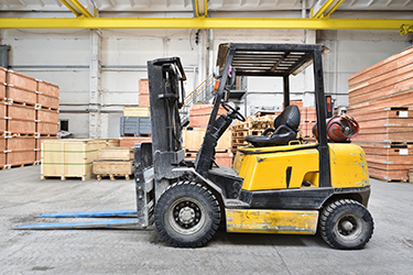 Forklift in warehouse with stacked boxes